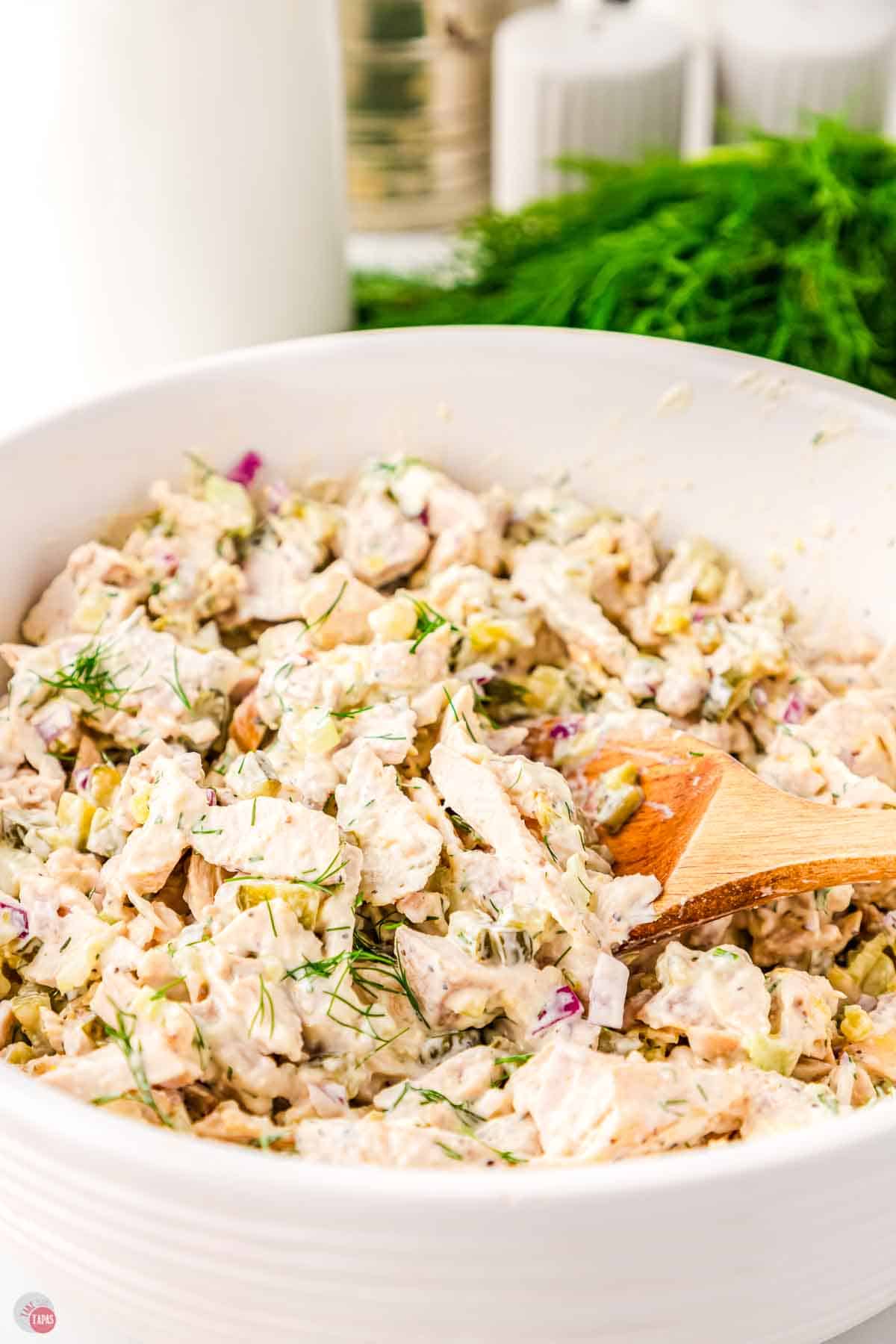 close up of mixed chicken salad with a wood spoon