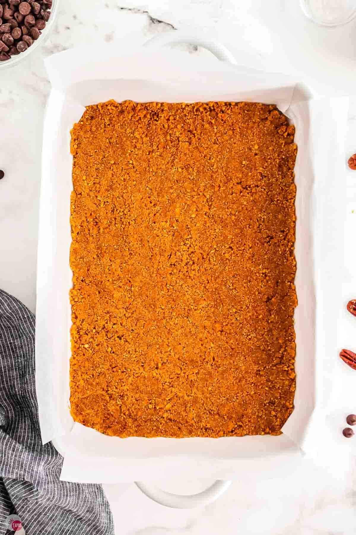 graham cracker crust in a 9x13 baking dish with parchment paper