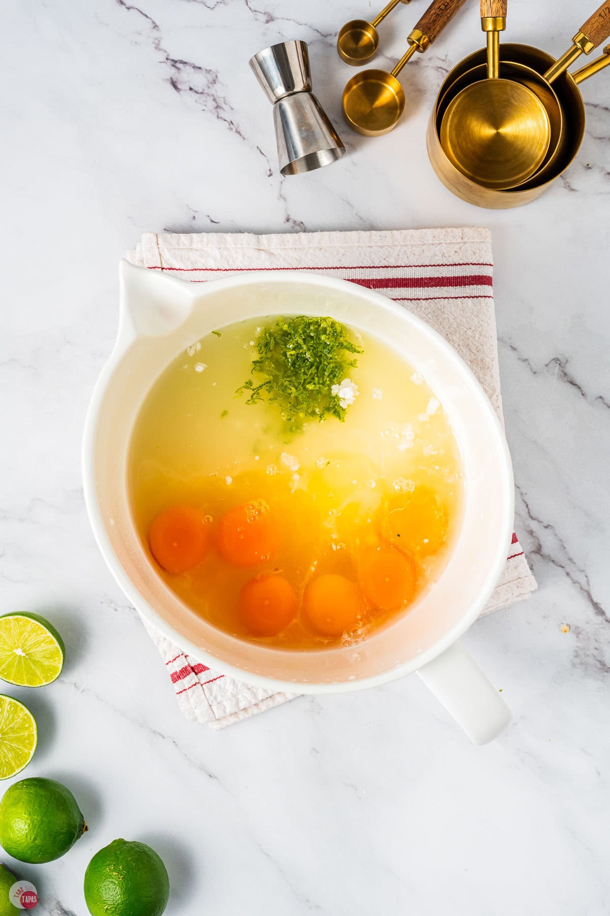 white mixing bowl with eggs, lime juice, lime zest, and sugar