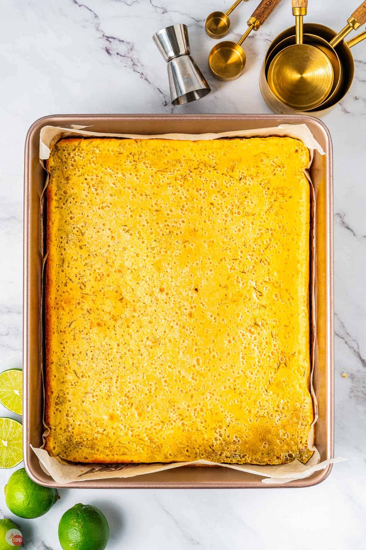 baked lime bars in a square dish with parchment paper