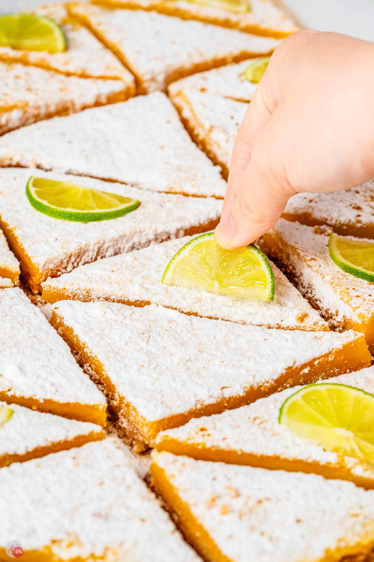 margarita bars sliced into triangles being topped with a lime slice