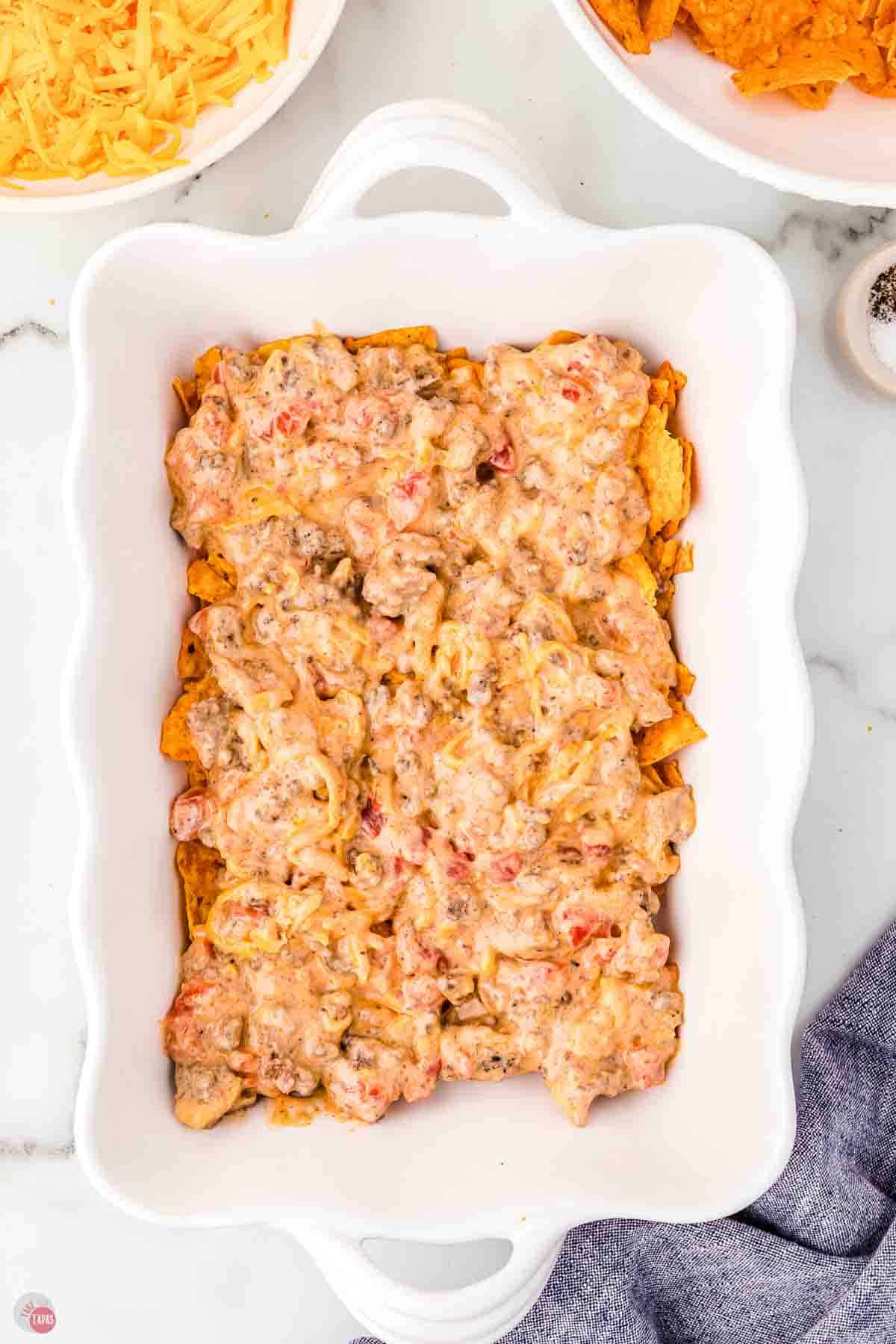 white baking dish with ground beef mixture on top of crushed chips