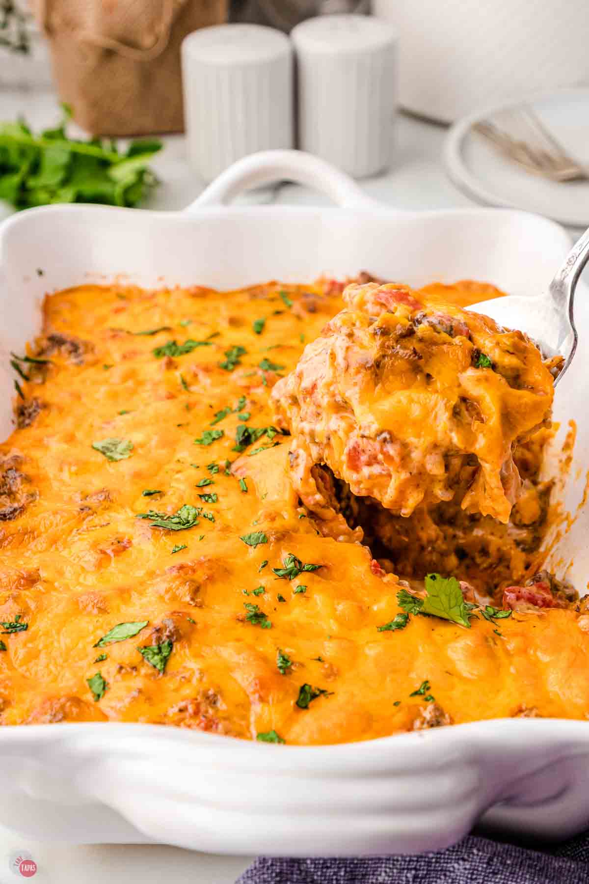 spoon scooping a cheesy casserole out of a dish