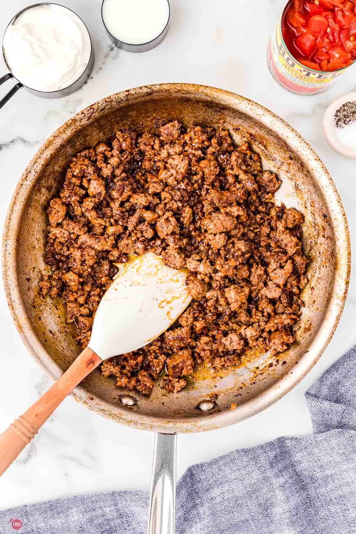 cooked ground beef in a skillet with a white spatula