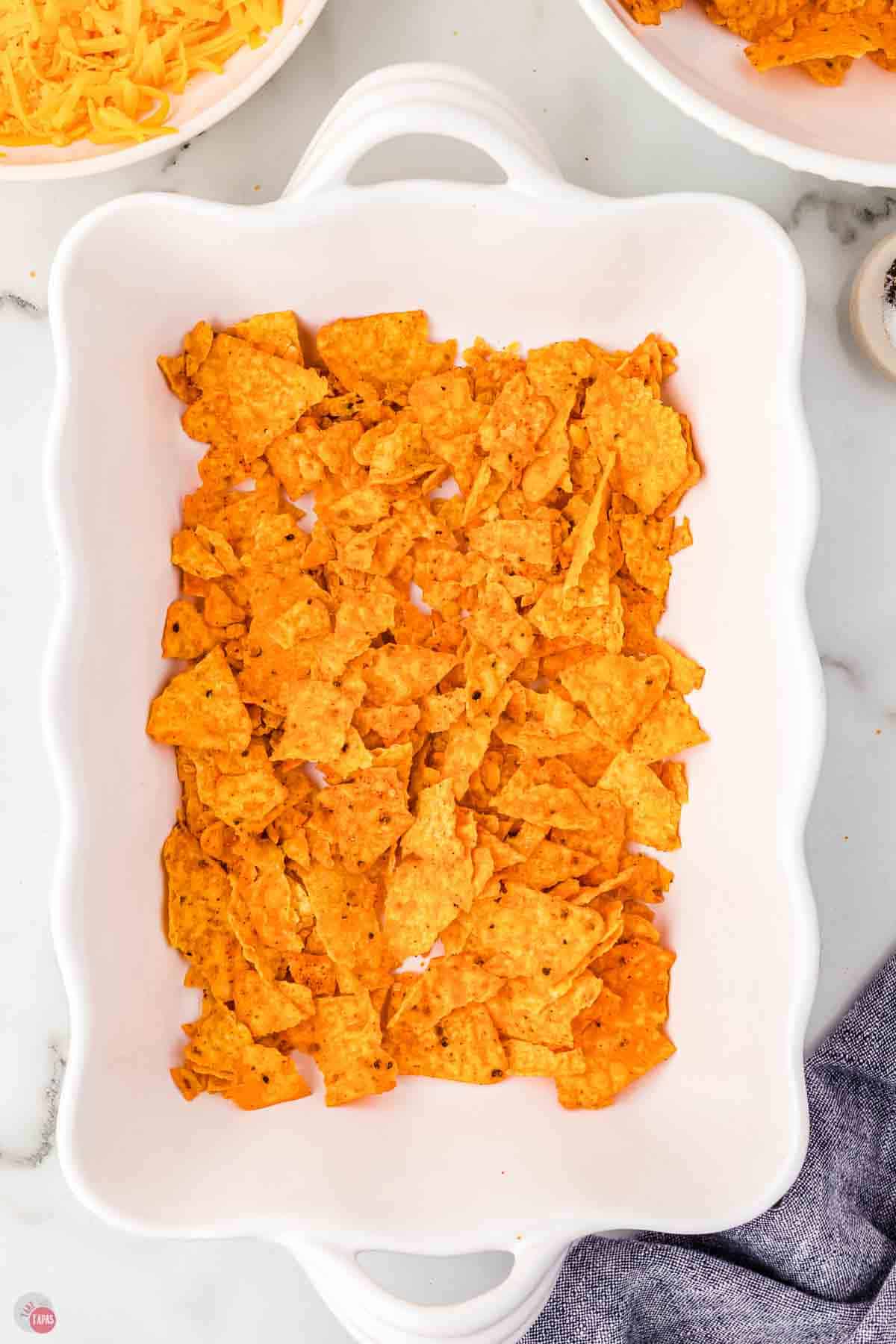 white casserole dish with crushed nacho chips in the bottom