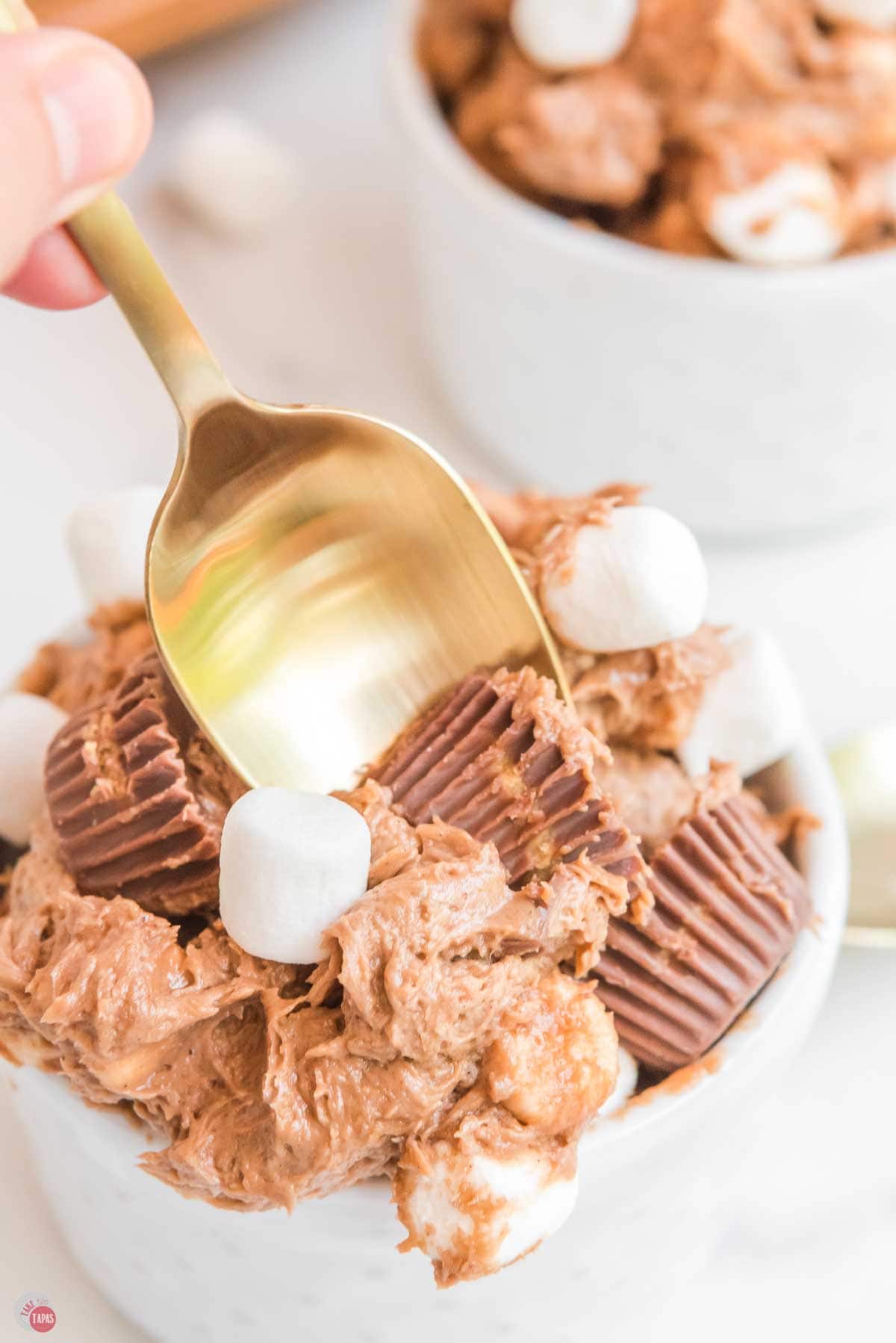 gold spoon scooping some peanut butter cups out of a white bowl