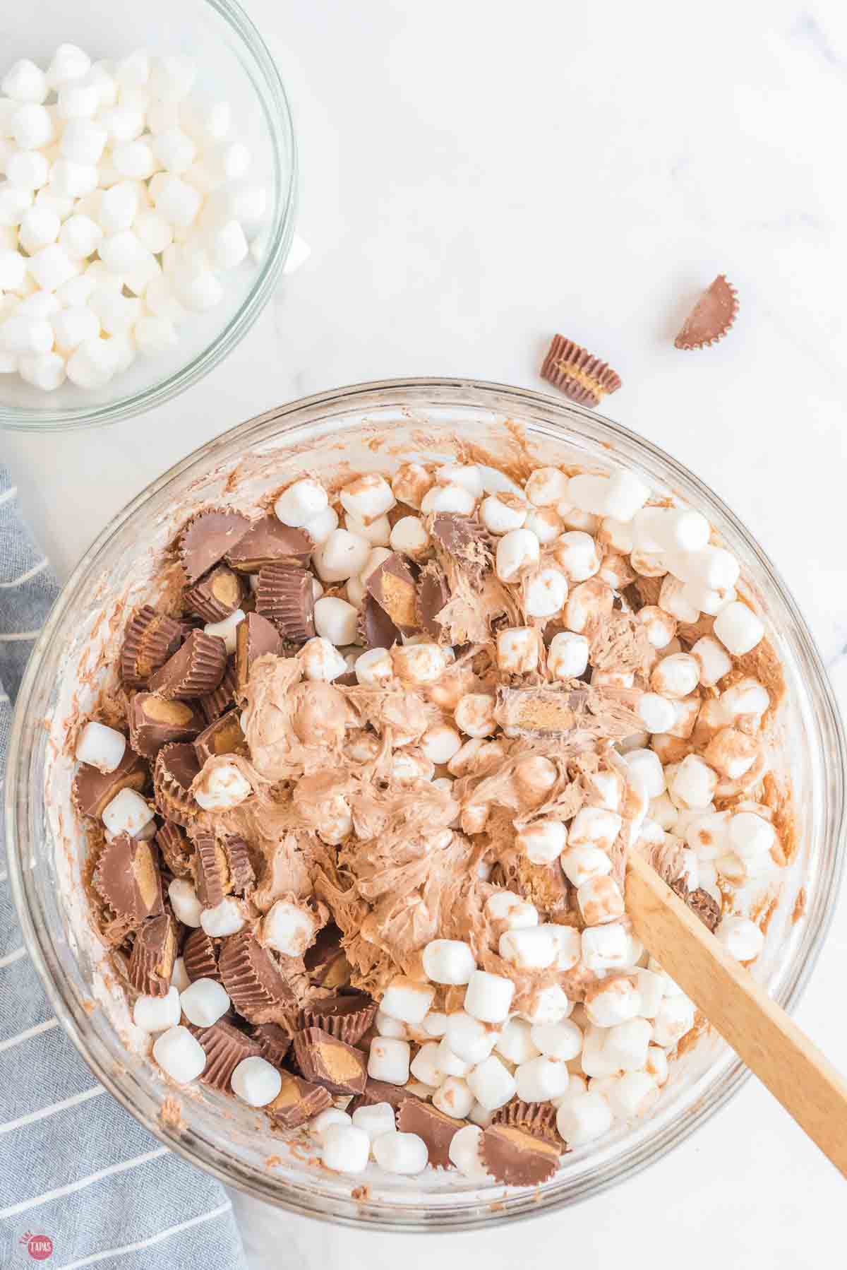 clear bowl with fluff salad being mixed by a wood spatula