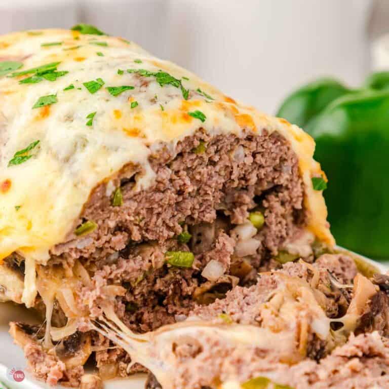 Cheesesteak meatloaf topped with cheese and a few slices cut off