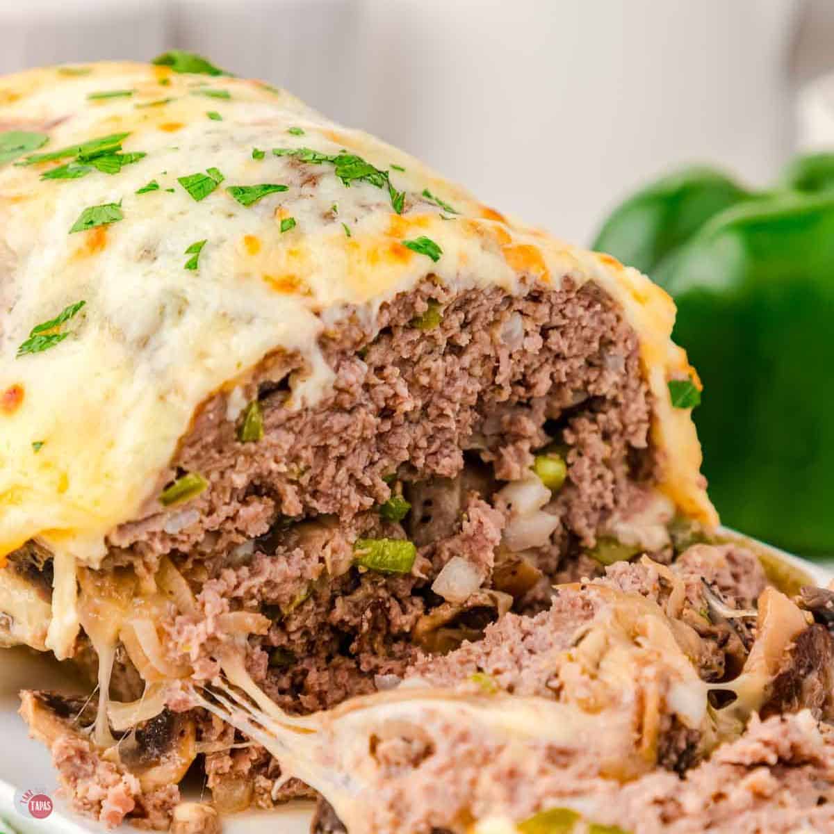 Cheesesteak meatloaf topped with cheese and a few slices cut off