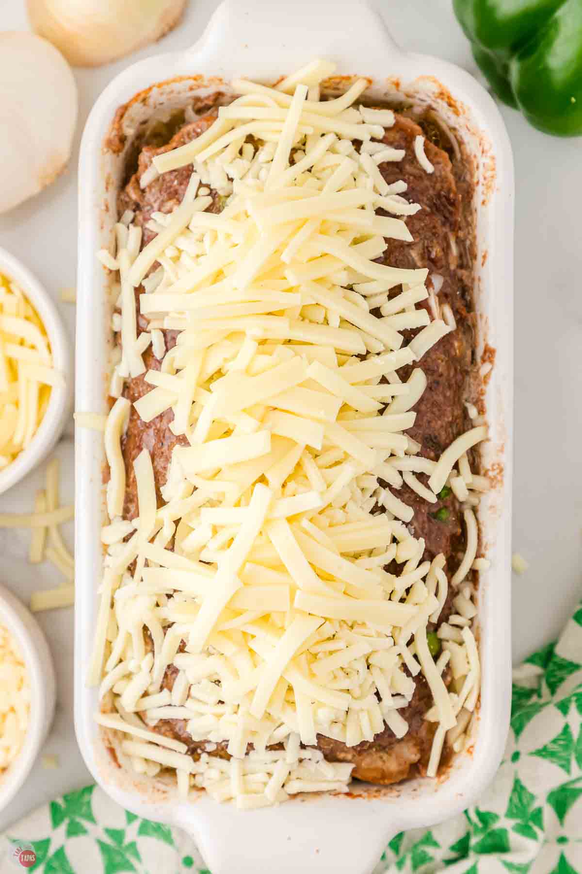 cooked meatloaf in a white rectangle dish topped with shredded cheese