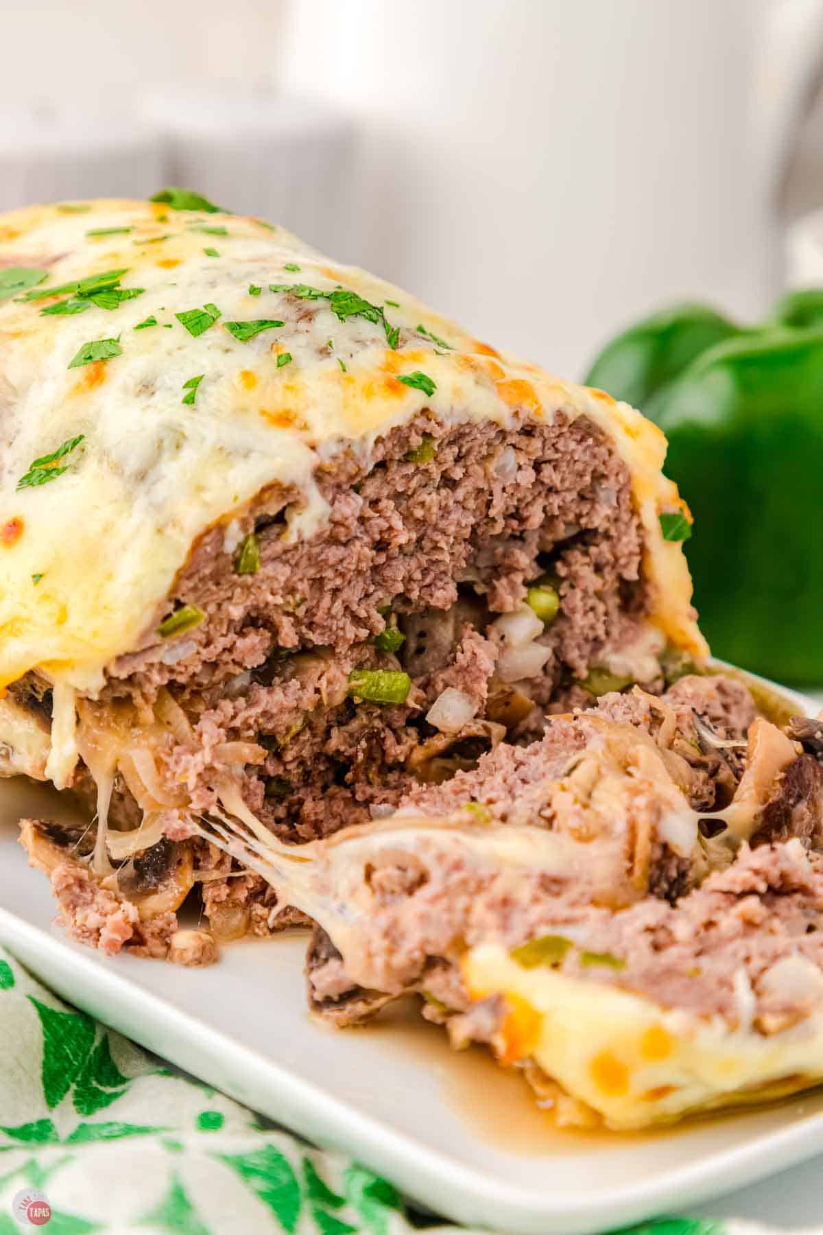 meatloaf topped with cheese and some slices laying next to it