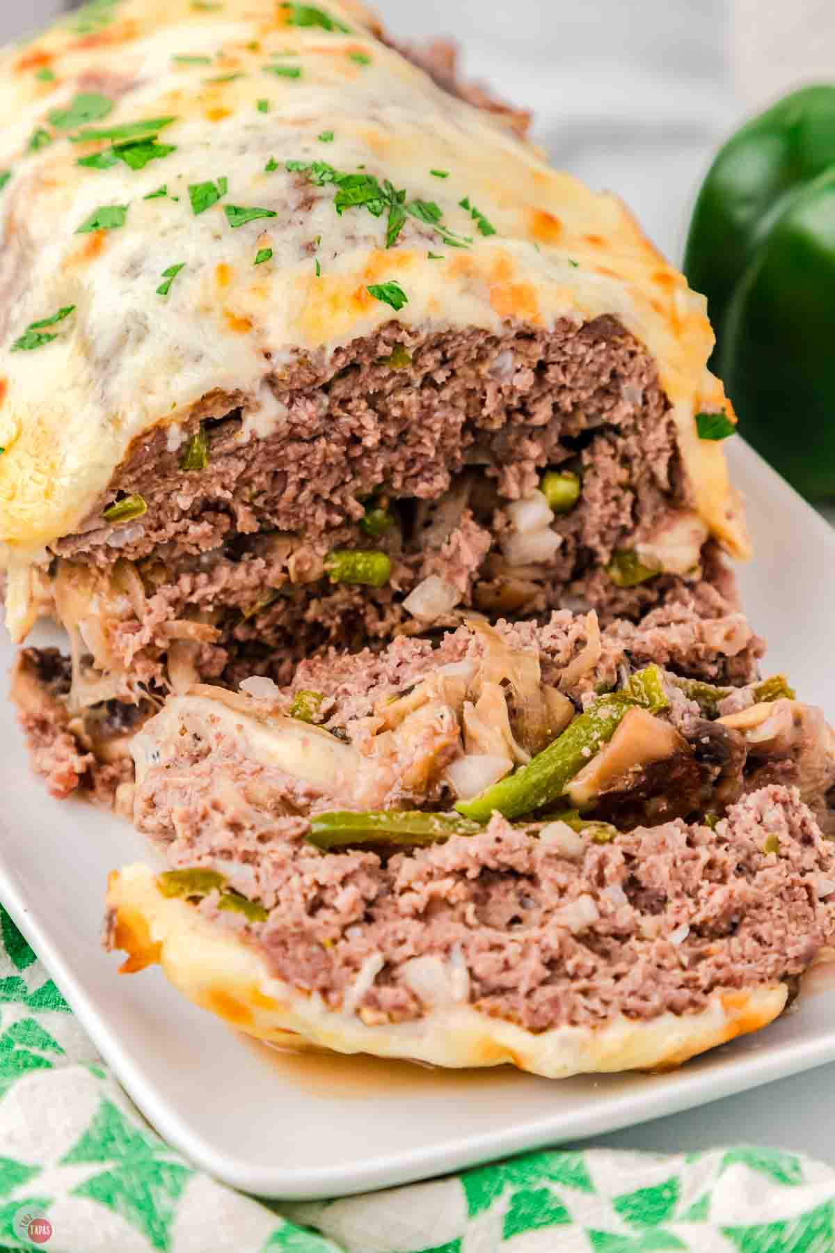 sliced meatloaf on a white plate topped with cheese