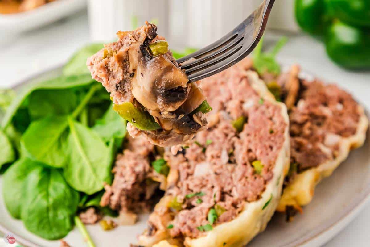 fork with bite of meat and mushrooms