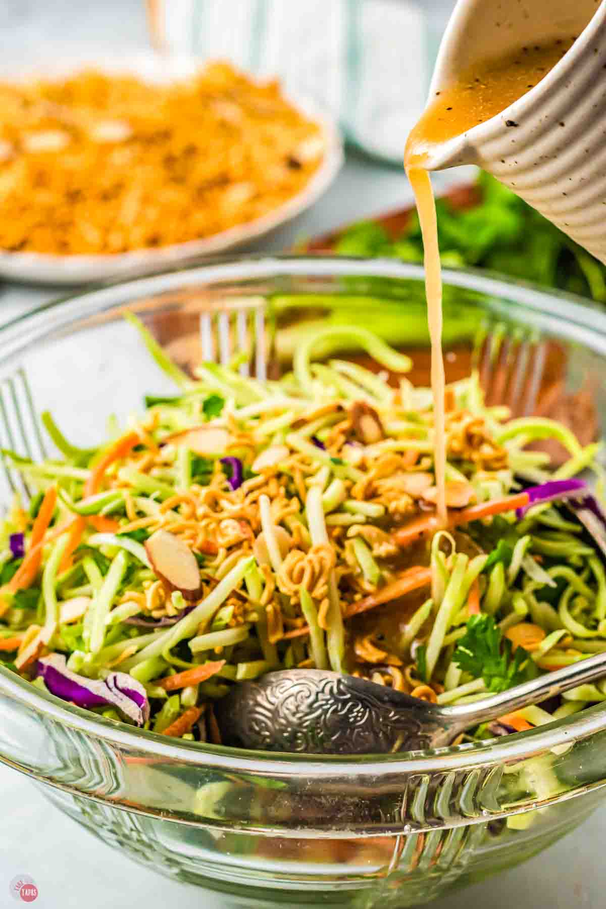 dressing pouring onto a bowl of slaw