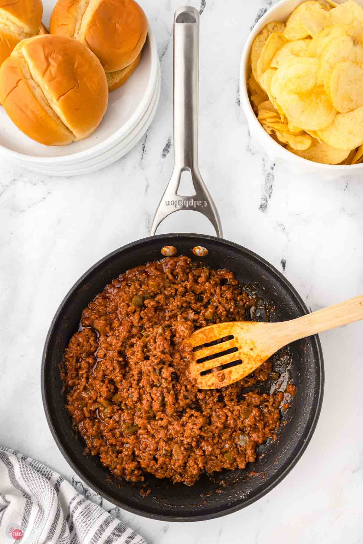 sloppy joe meat mixture in a skillet with a wood spoon