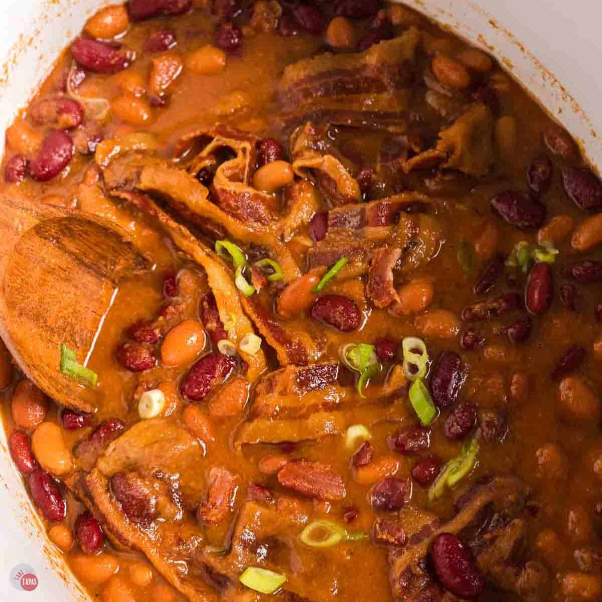 white crock pot with beans and bacon