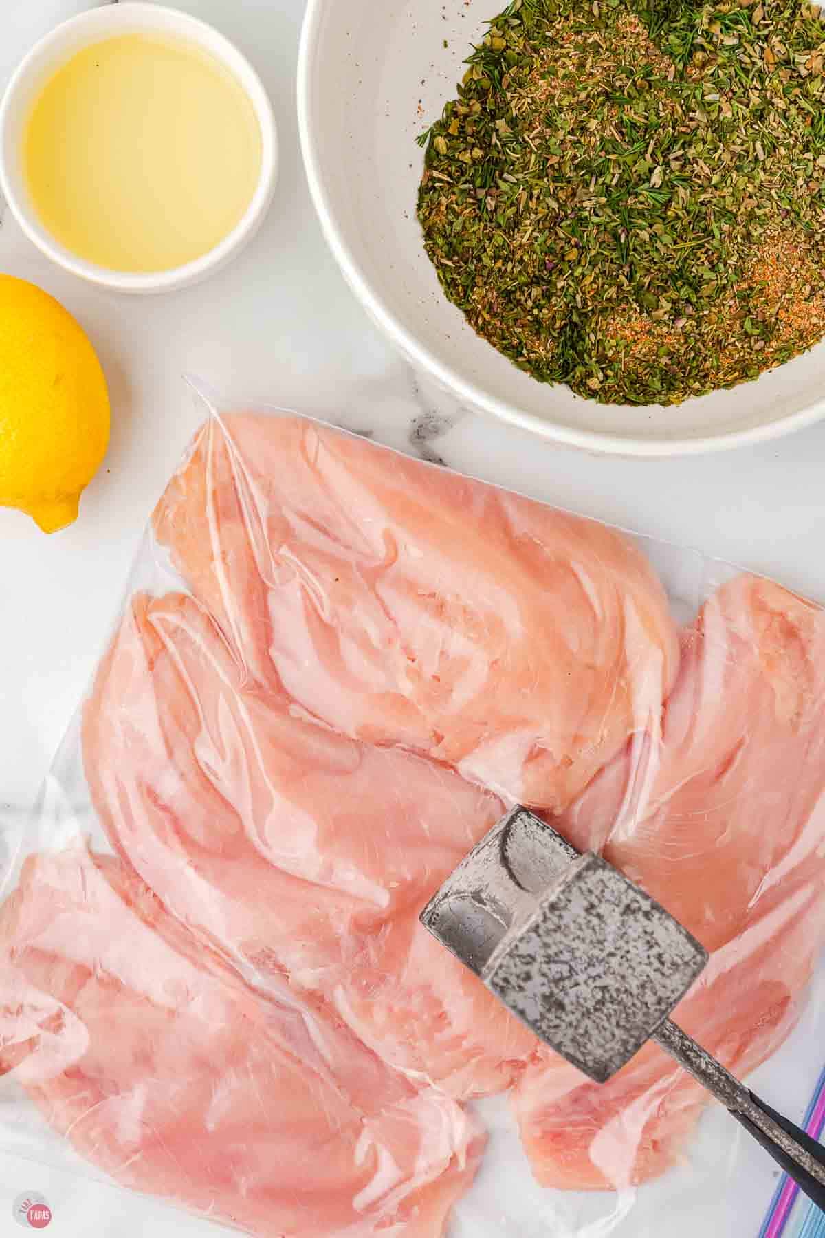 mallet pounding chicken breasts in a plastic bag