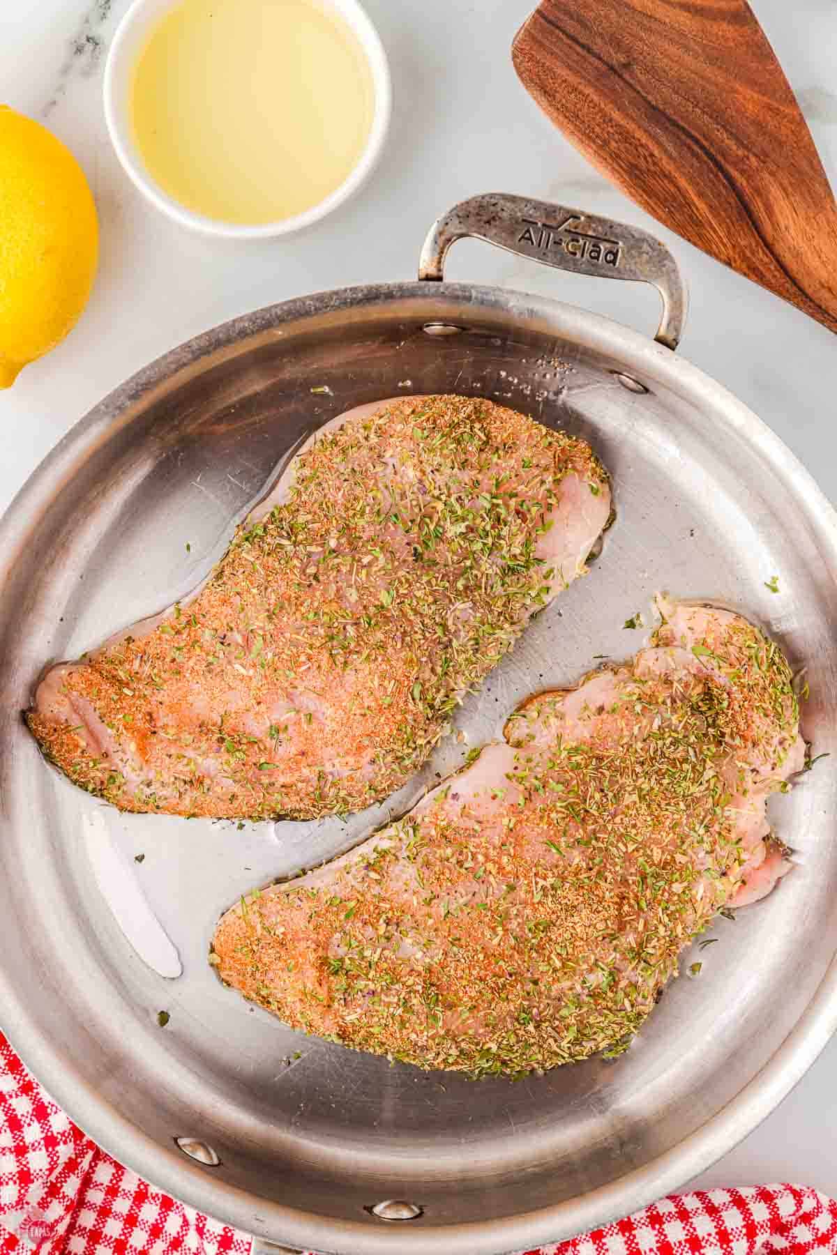 two chicken breasts pan searing in skillet