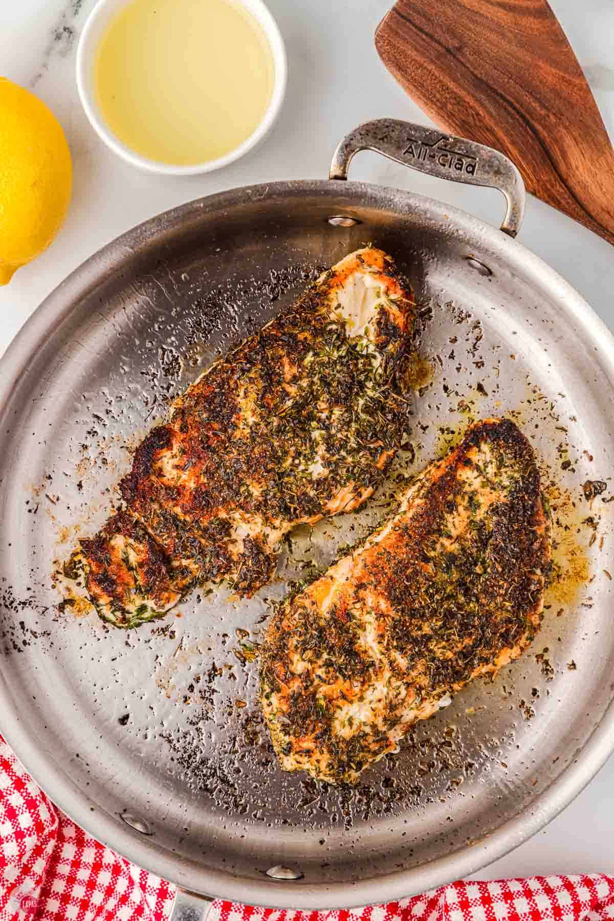 skillet with two chicken breasts cooking in it