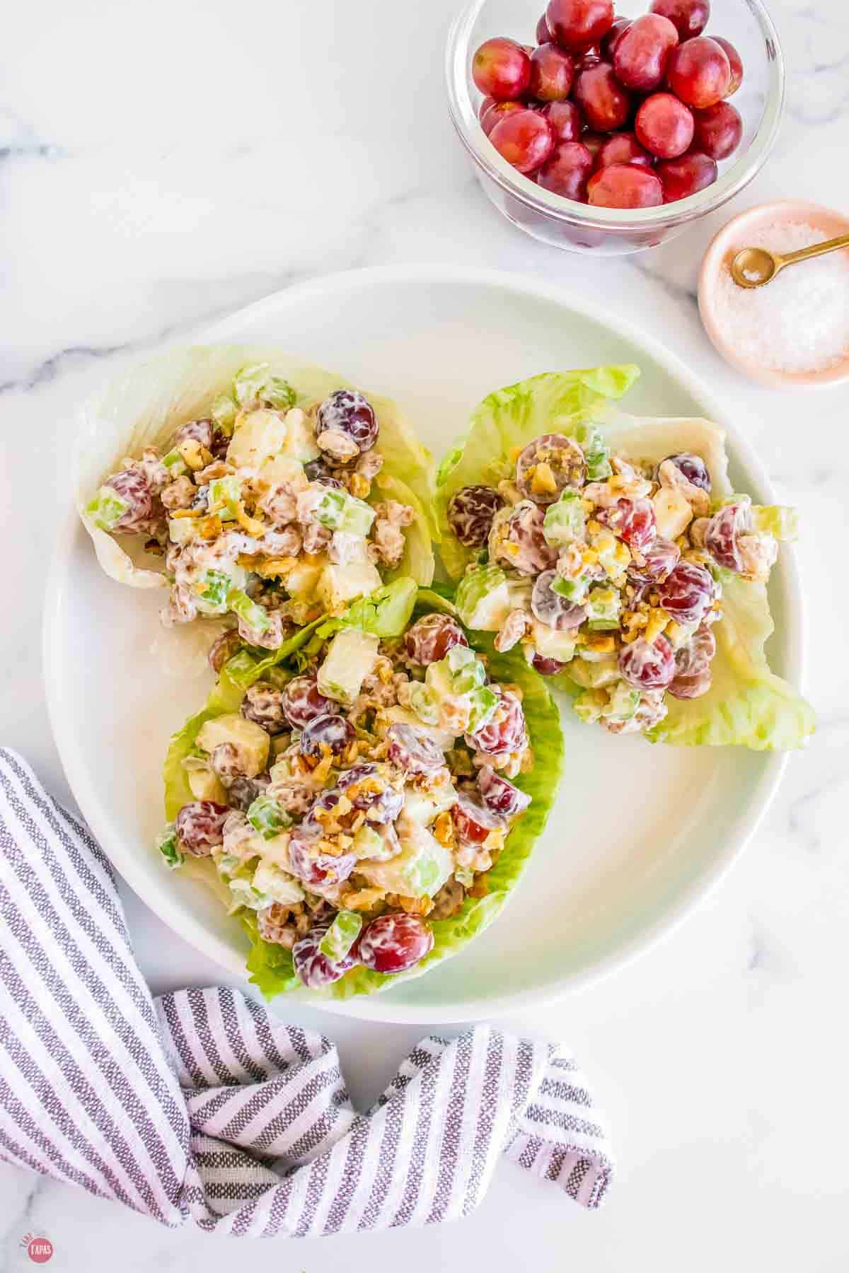 white plate with three lettuce cups with salad in them