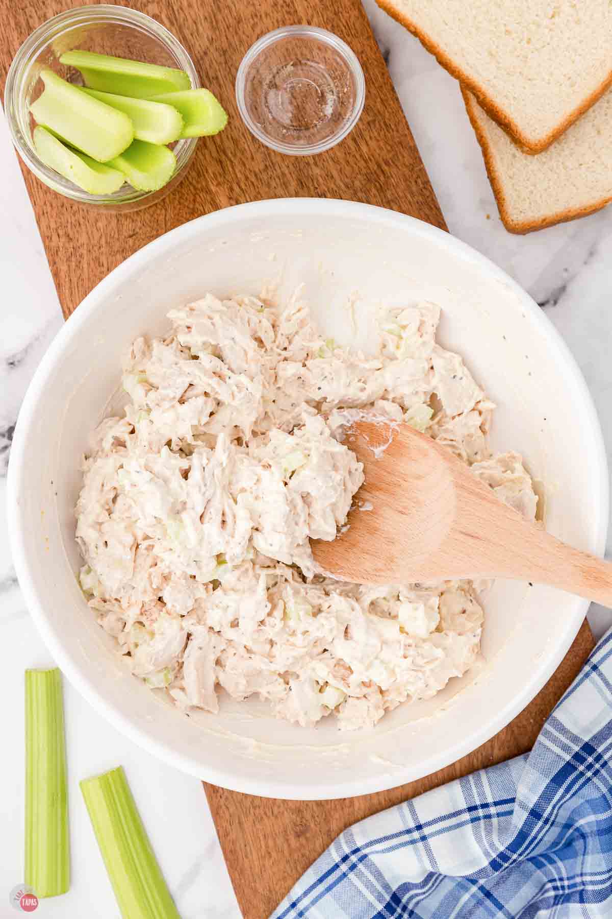 chicken salad in a white bowl with a wood spoon
