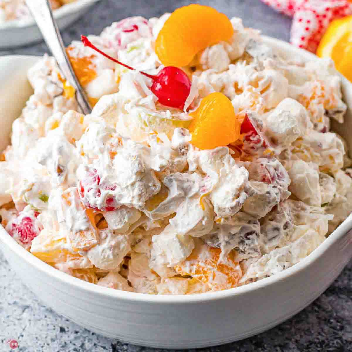 bowl of creamy ambrosia with oranges and cherries