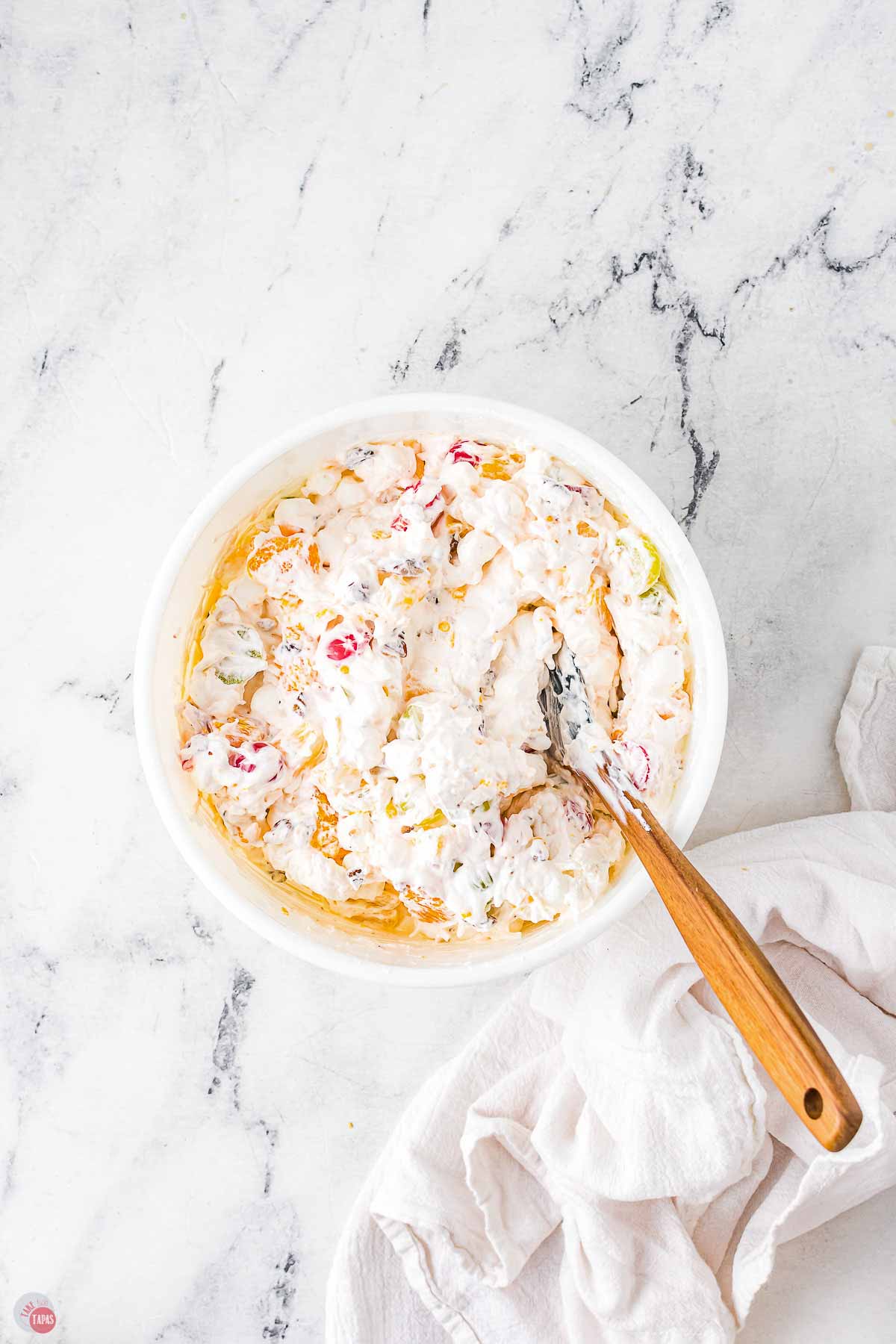 bowl of sour cream and whipped topping being mixed with fruit