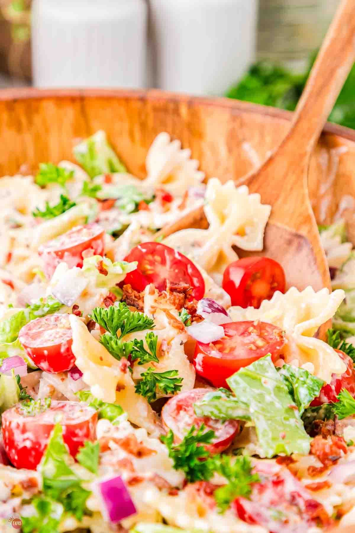 wood spoon scooping pasta salad out of a bowl