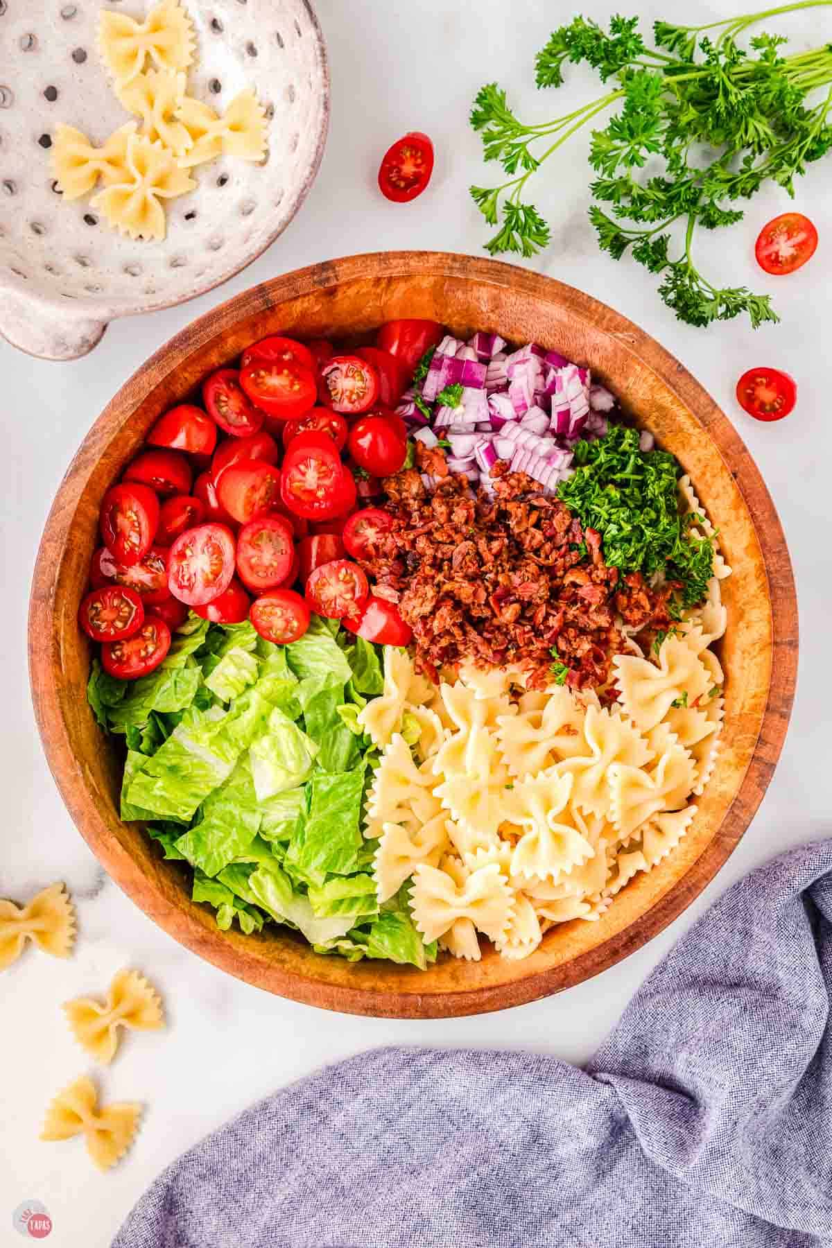 wood bowl with cooked pasta and chopped vegetables