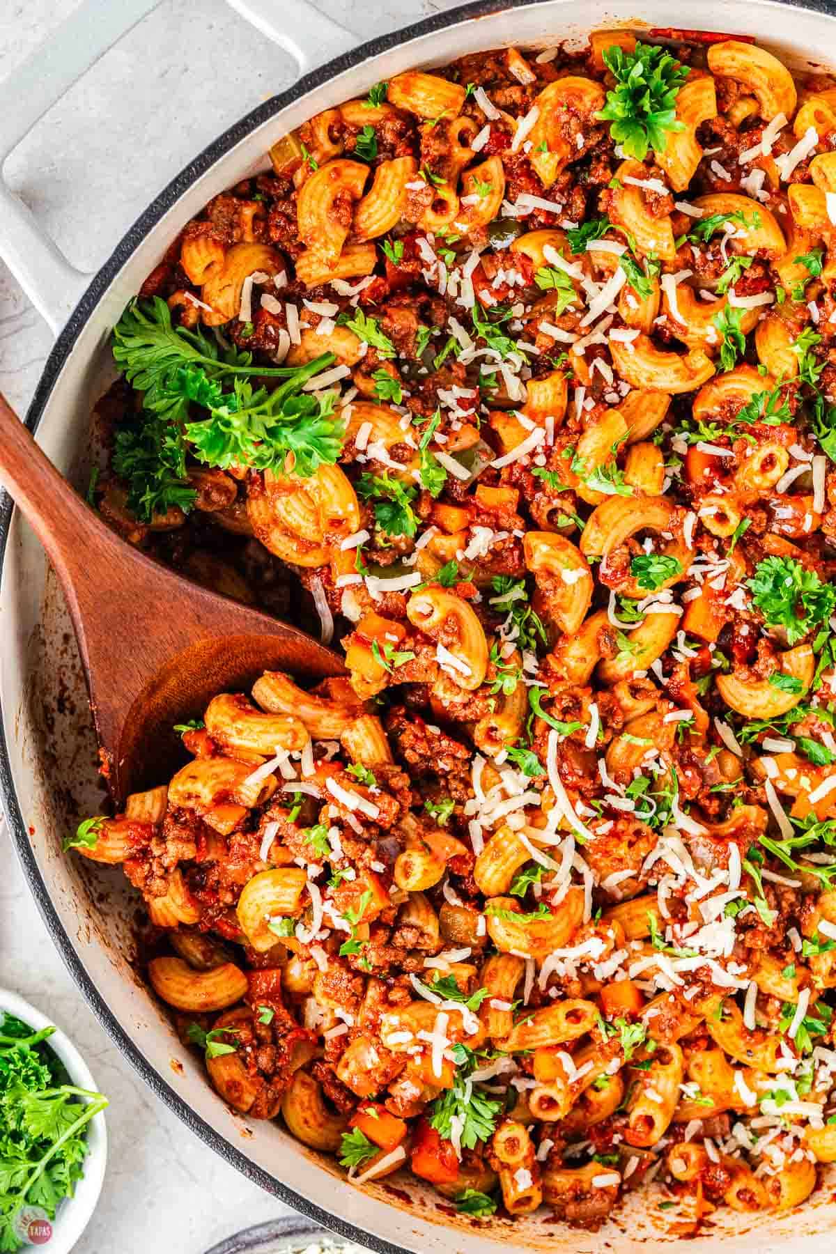 close up of pot of beefaroni with a wood spoon