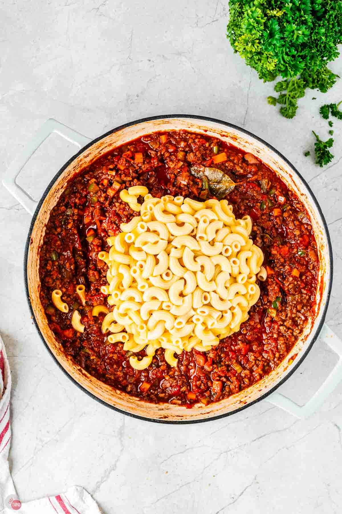 cooked pasta noodles on top of a pot of sauce