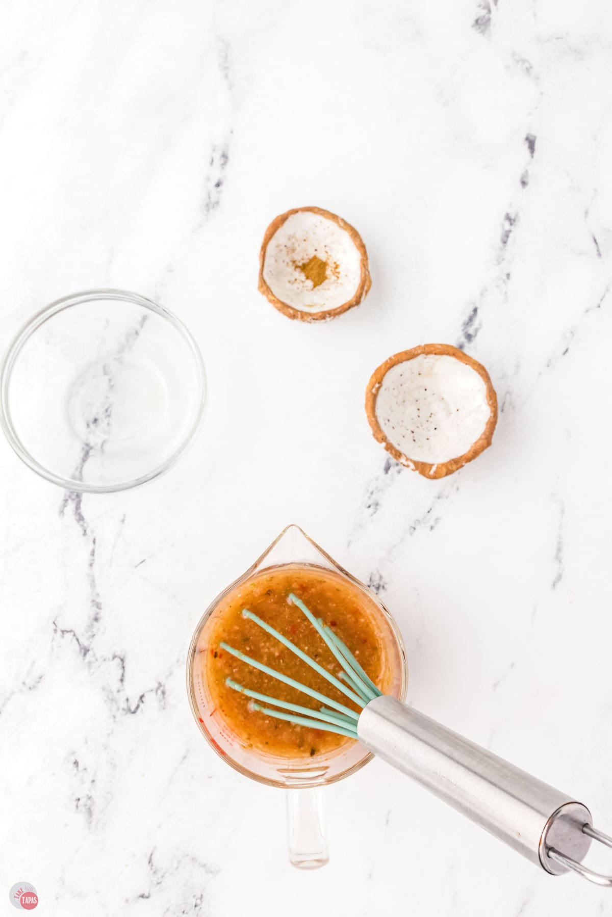 small measuring cups with a small bowl of dressing and a whisk