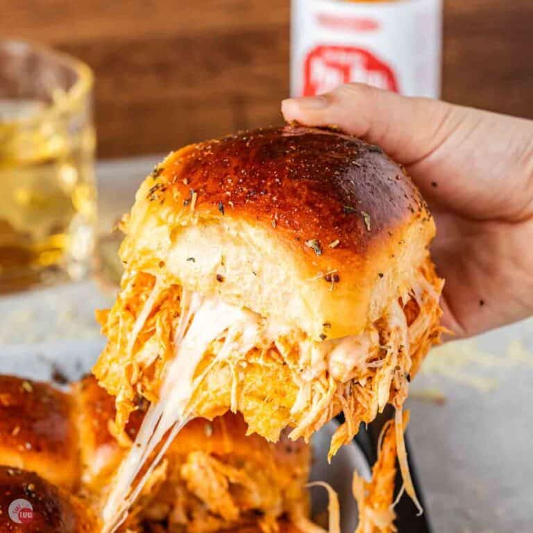 hand pulling a chicken slider out of a pan