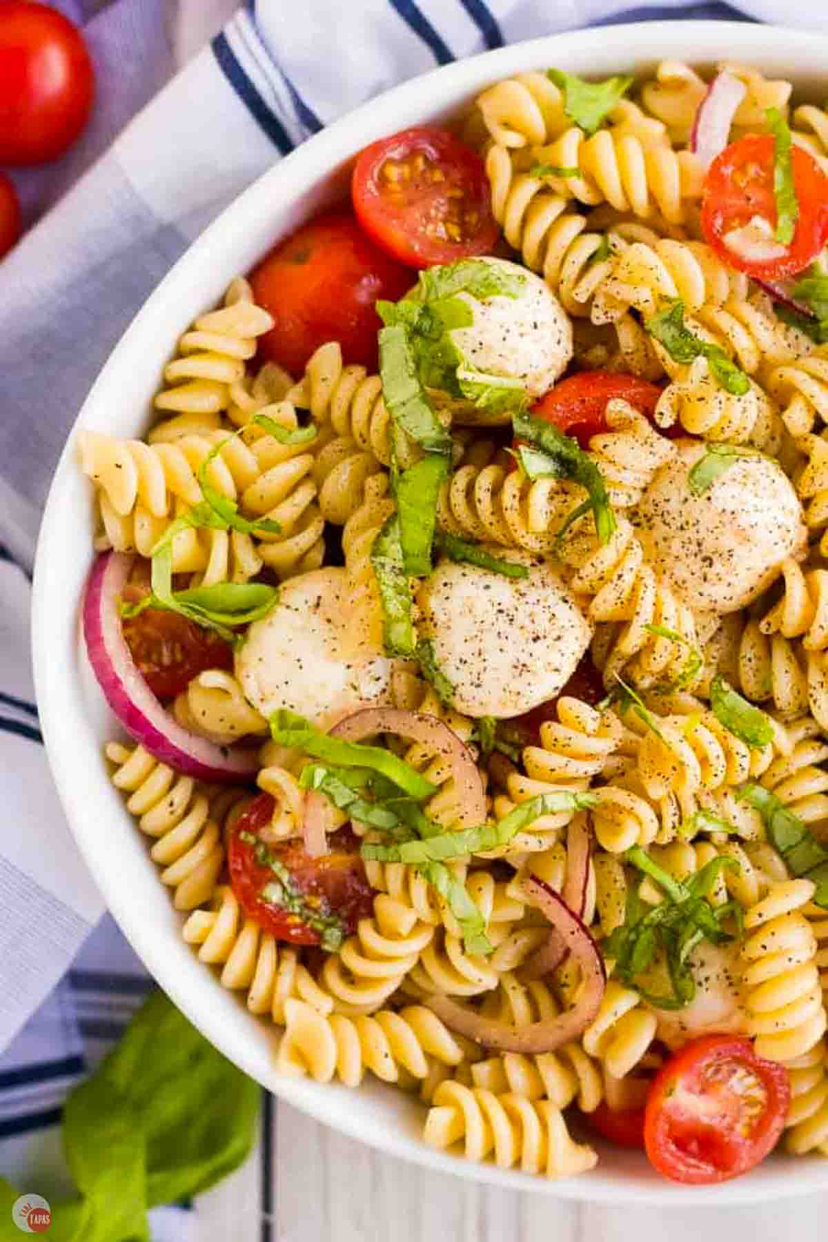 close up of caprese pasta salad in a white bowl