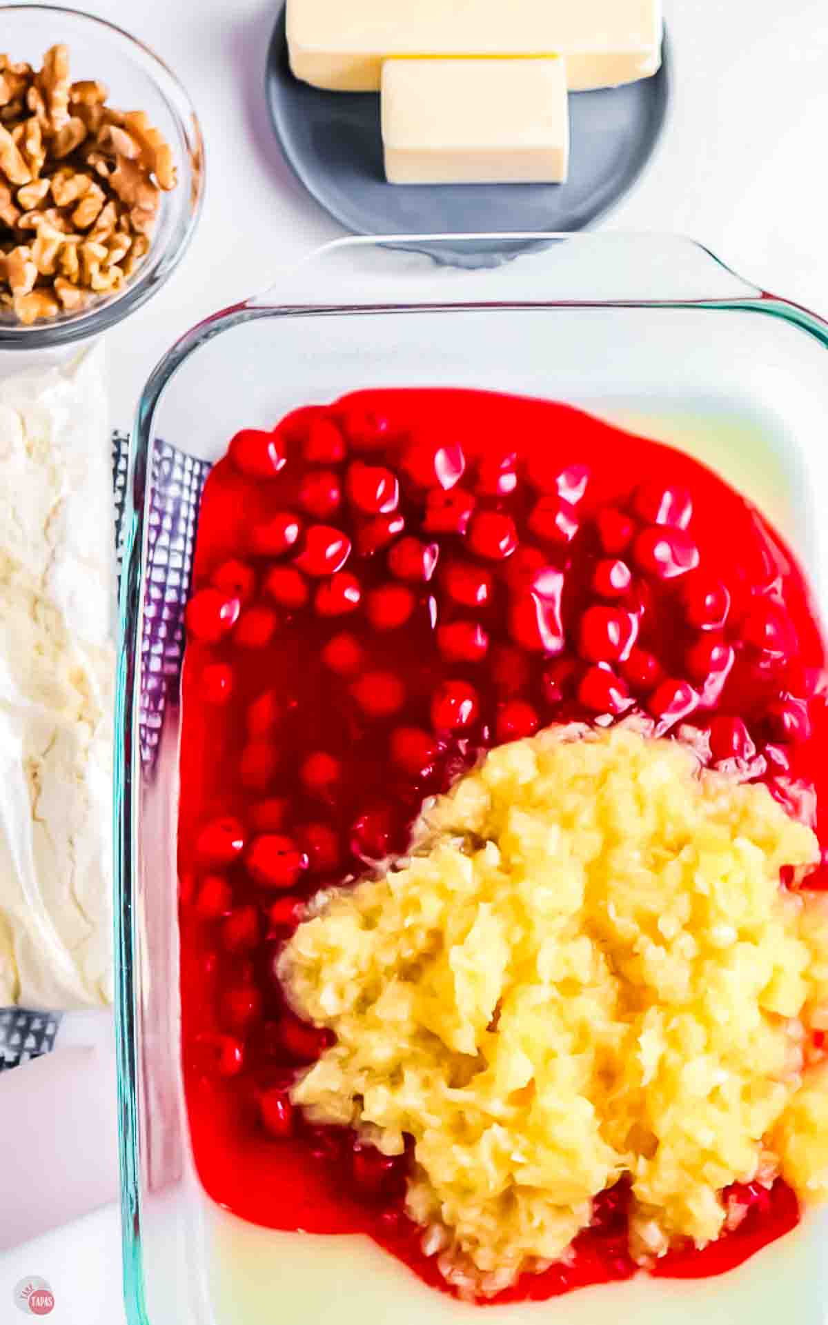 clear baking dish with cherry pie filling and crushed pineapple in it