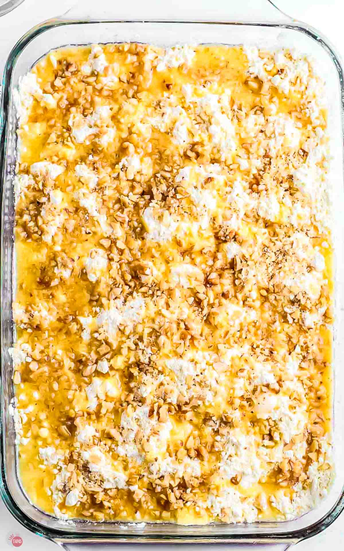 unbaked cake topped with walnuts in a clear baking dish