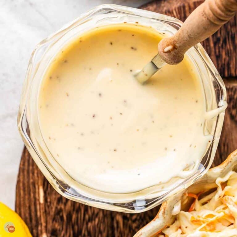 jar of dressing with a spoon next to a bowl of shredded cabbage