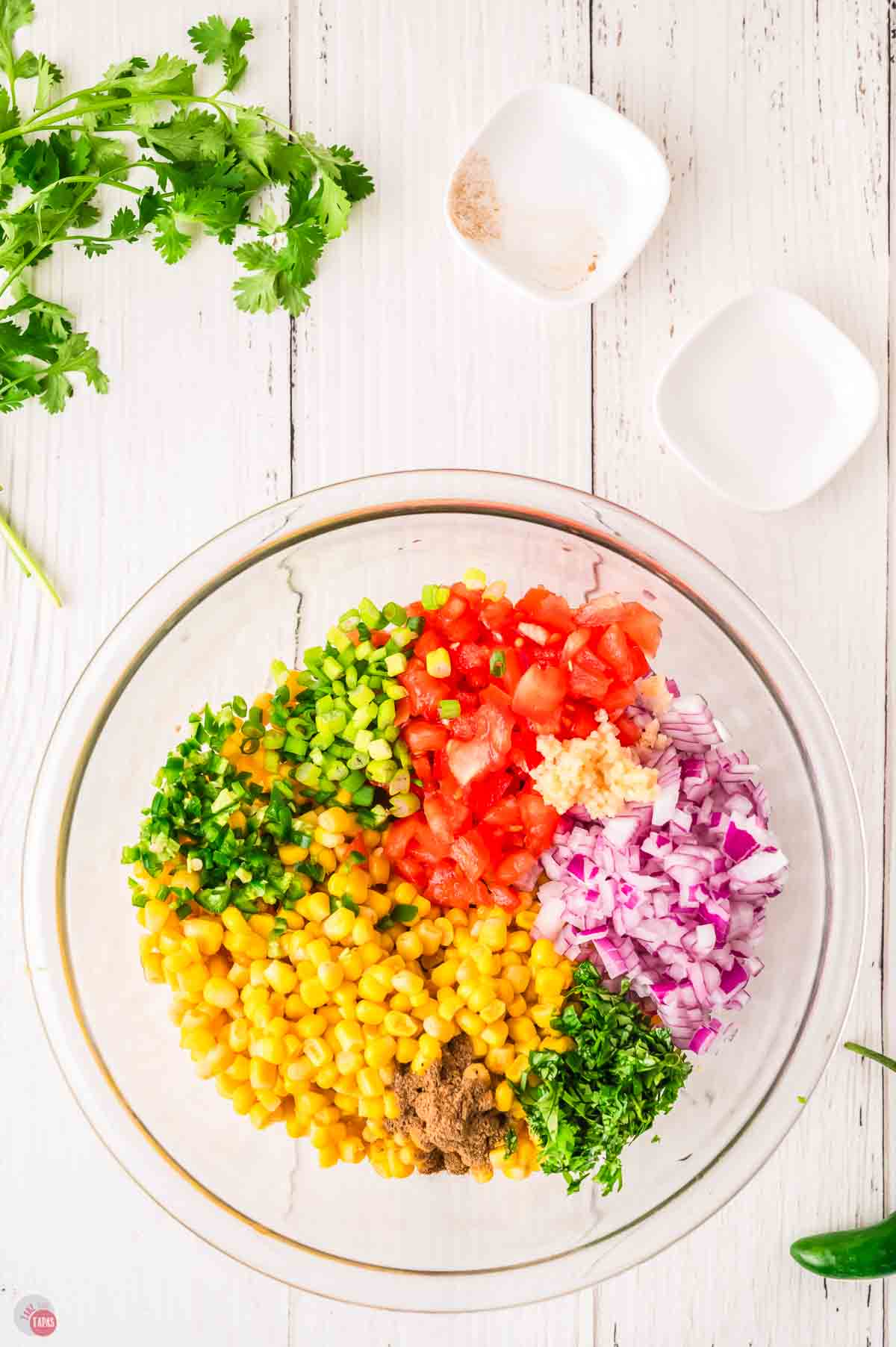 clear mixing bowl with corn, tomatoes, and vegetables in it
