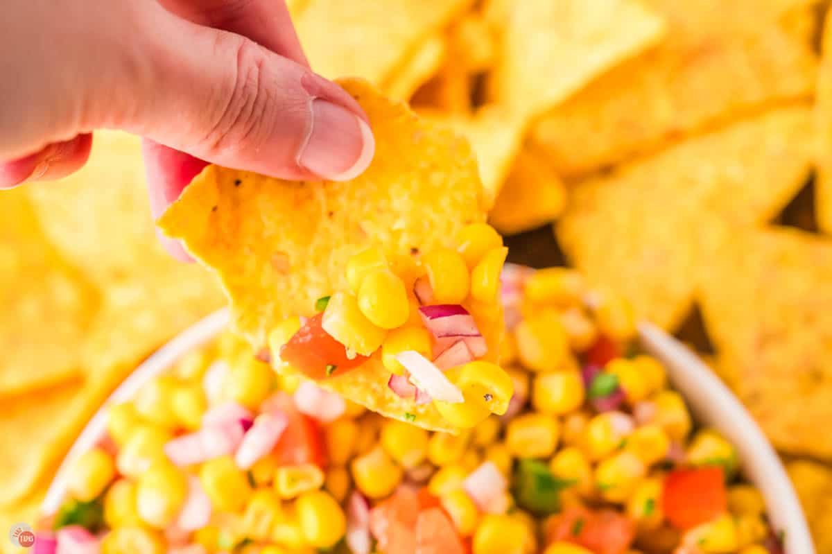 chip scooping salsa out of a bowl