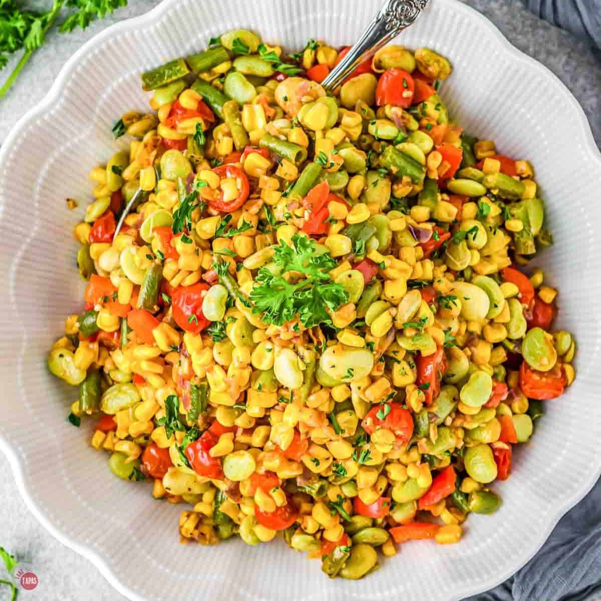 white bowl of corn succotash with parsley on top