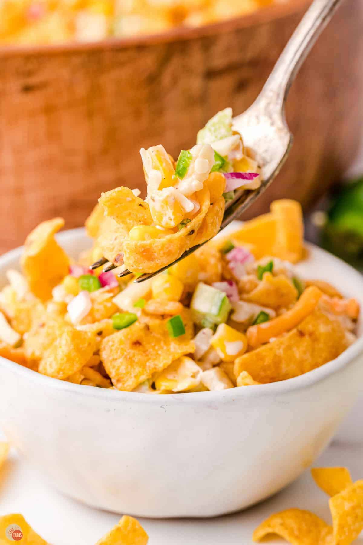 white bowl with salad and a hovering fork with a bite
