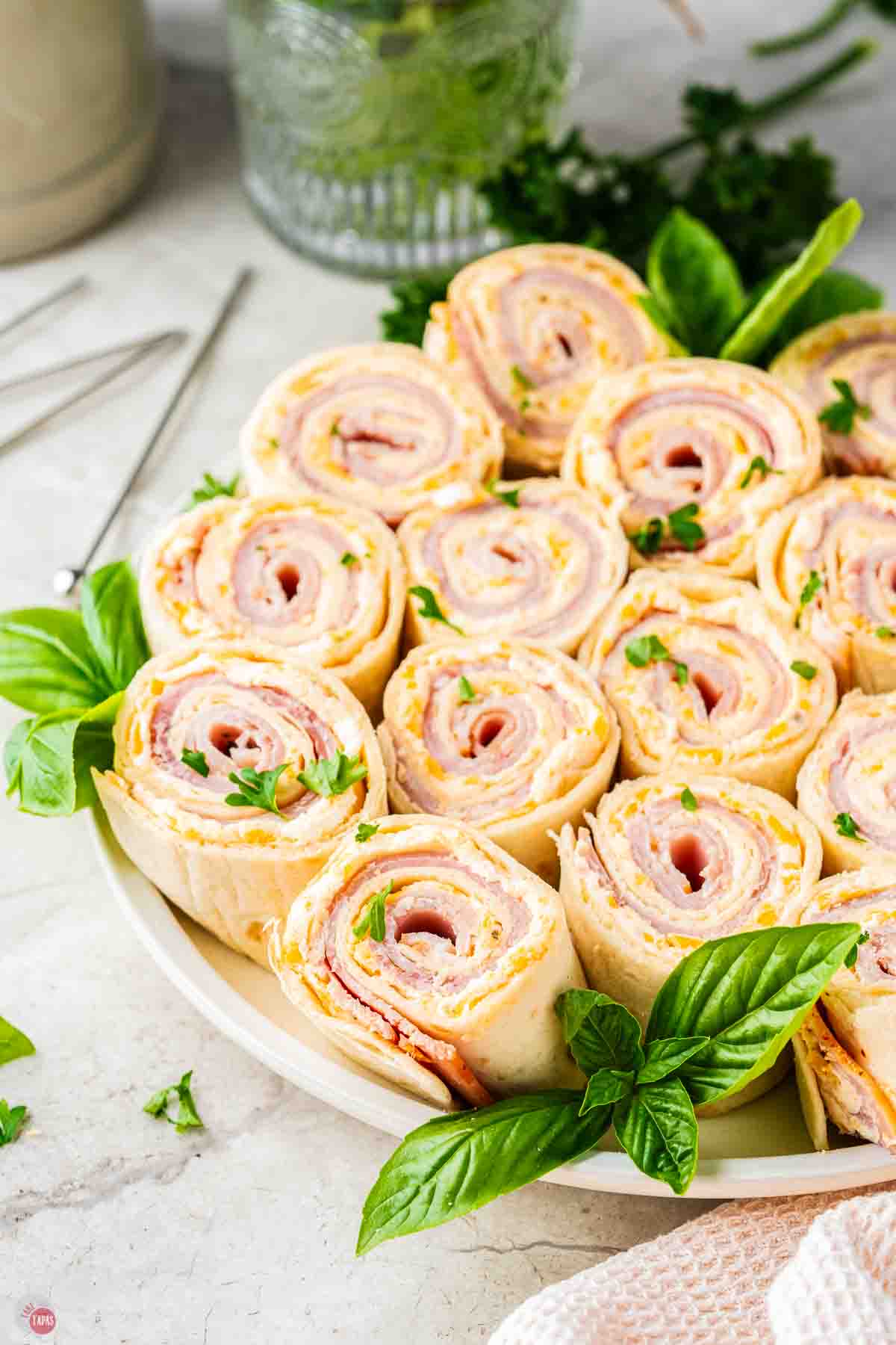 plate of ham and cheese pinwheels with fresh herbs
