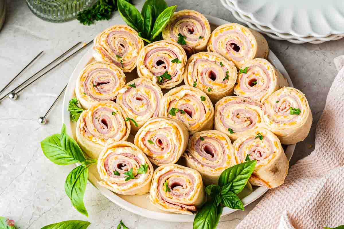 plate of ham and cheese roll up sandwiches