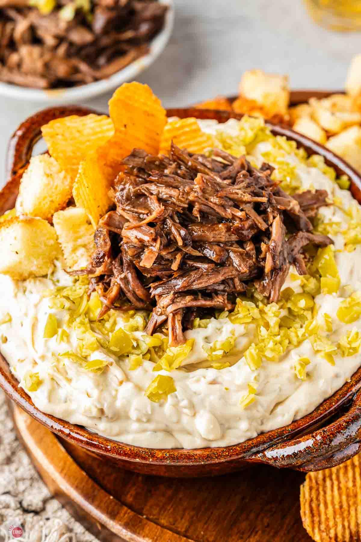 bowl of dip with chopped peppers and shredded beef on top