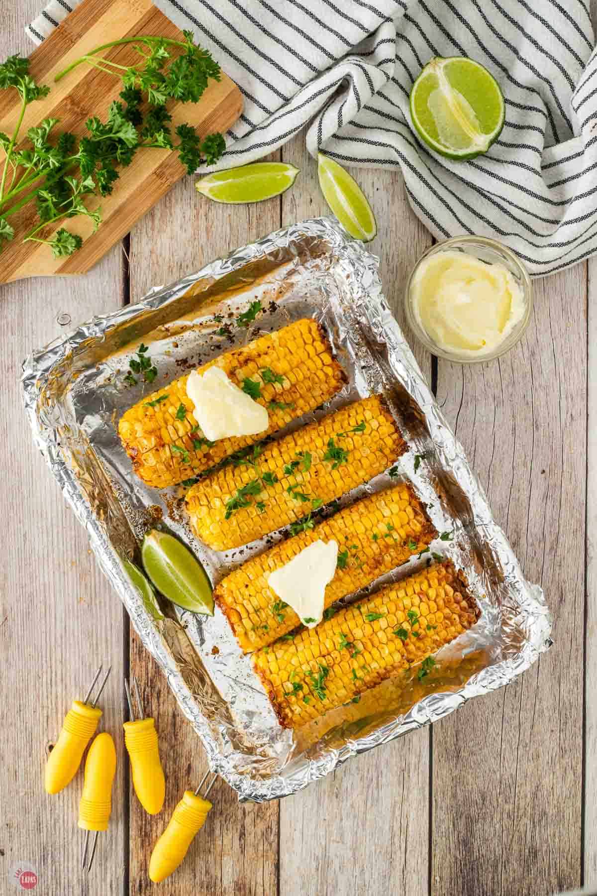 roasted corn topped with chopped herbs and pats of butter