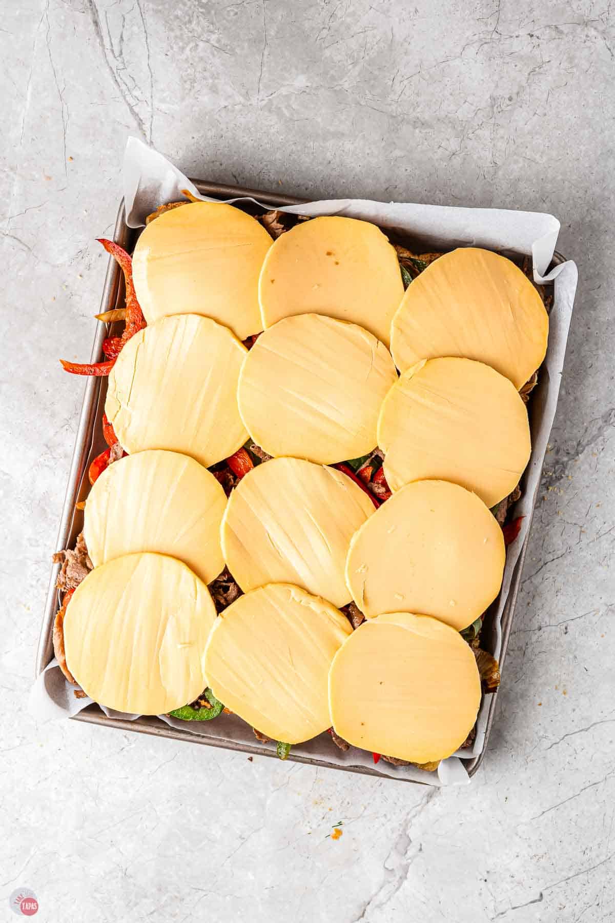 baking sheet with slider meat and topped with slices of cheese