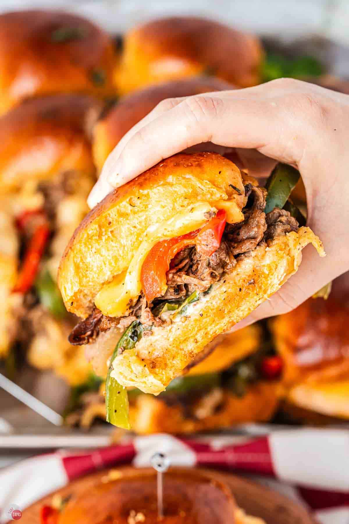hand holding a philly cheesesteak slider