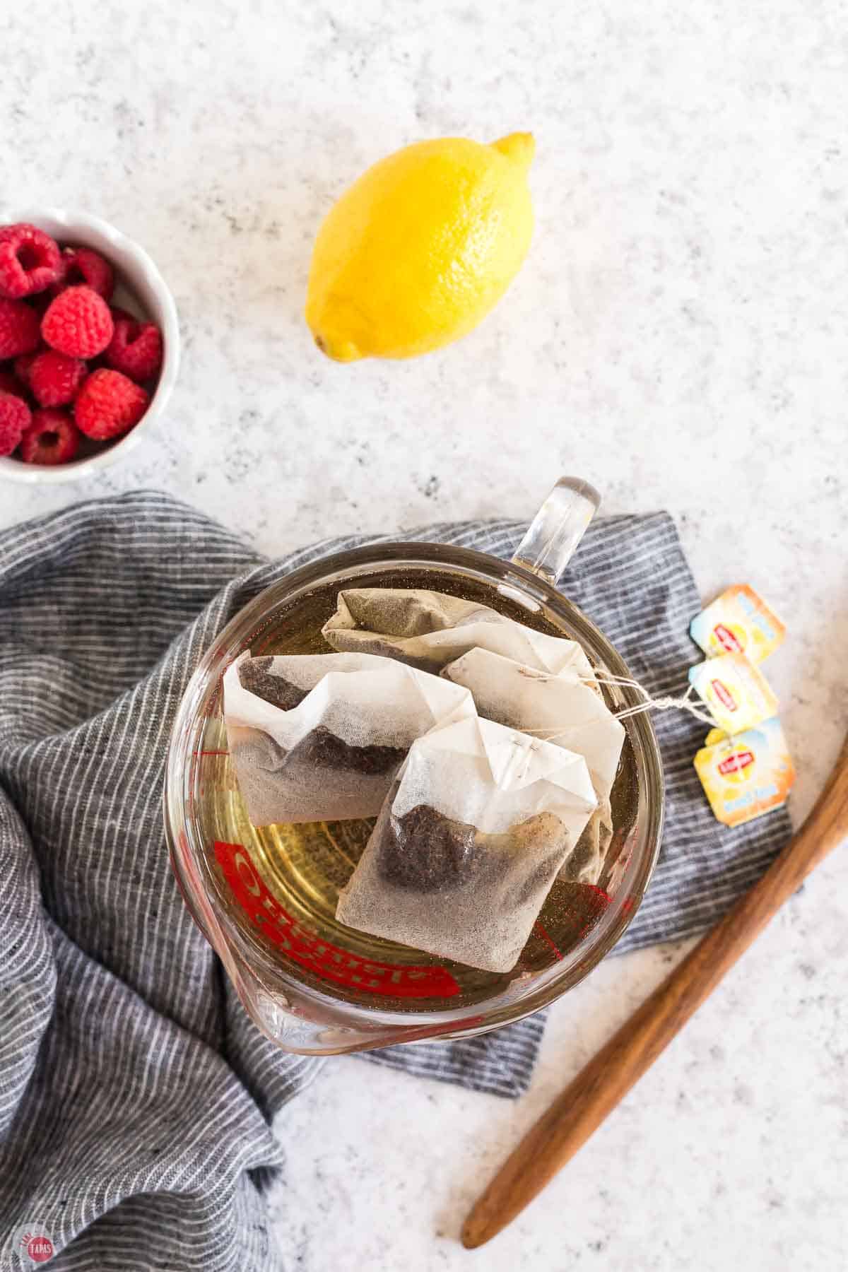 tea bags steeping in hot water in a glass measuring bowl