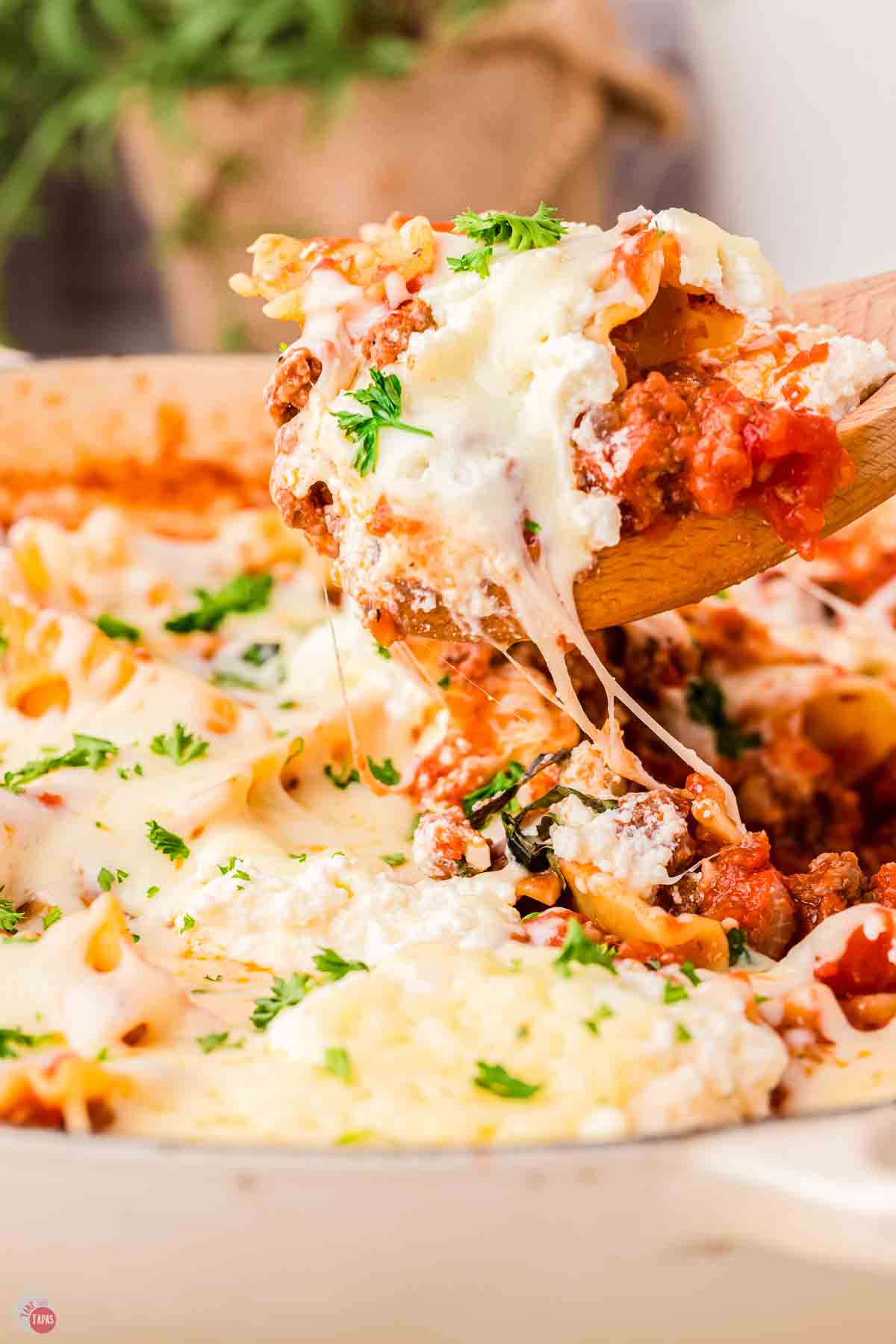 wood spatula scooping lasagna out of a skillet