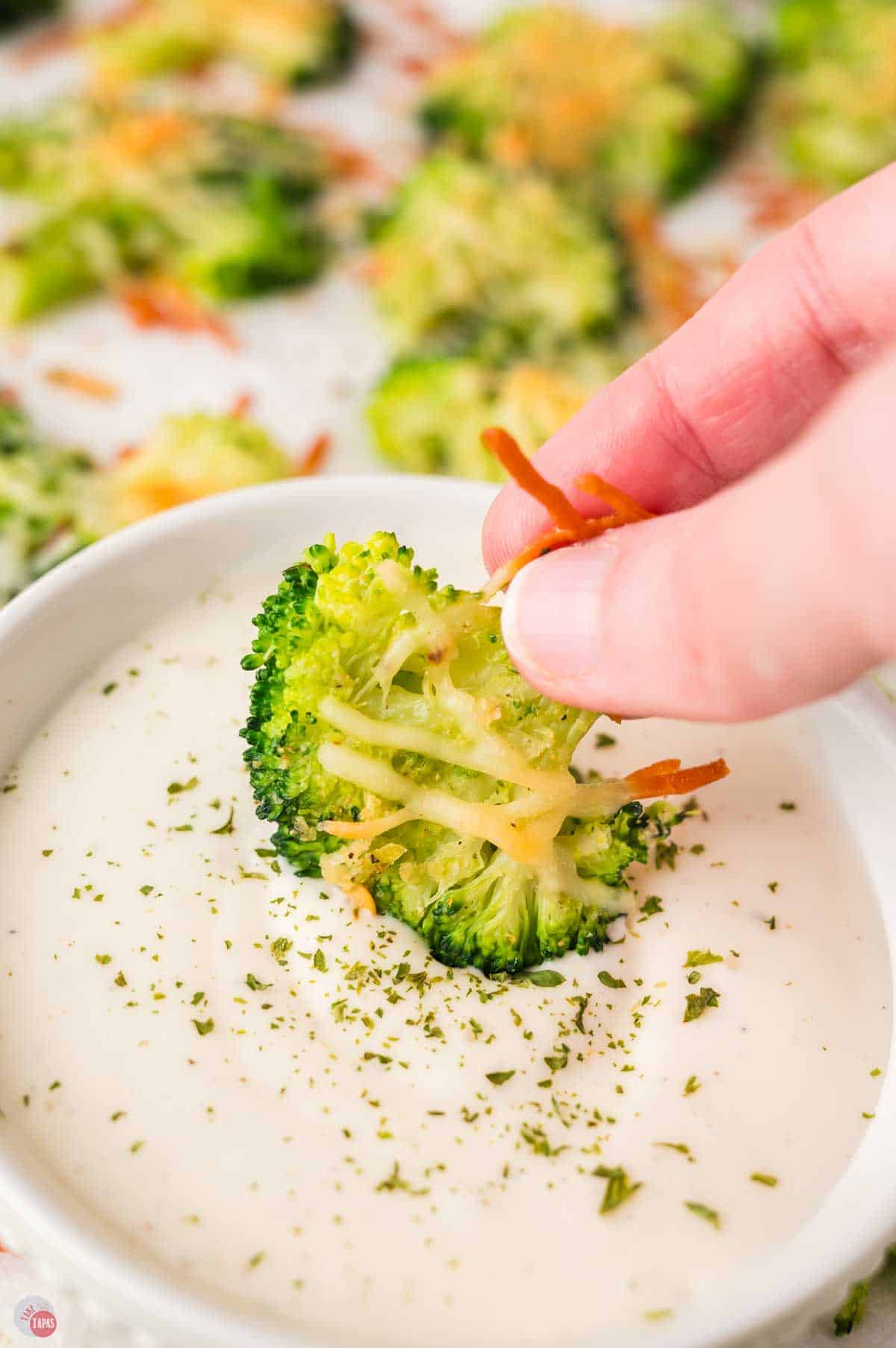 hand dipping vegetable in a bowl of ranch dressing